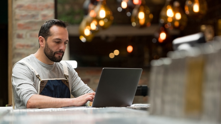 Restaurant owner checking his POS reports on a laptop.