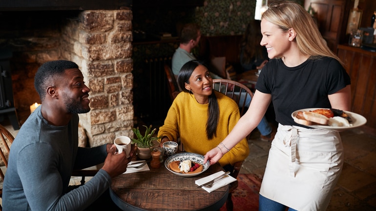 Female restaurant server delivering food to customers.