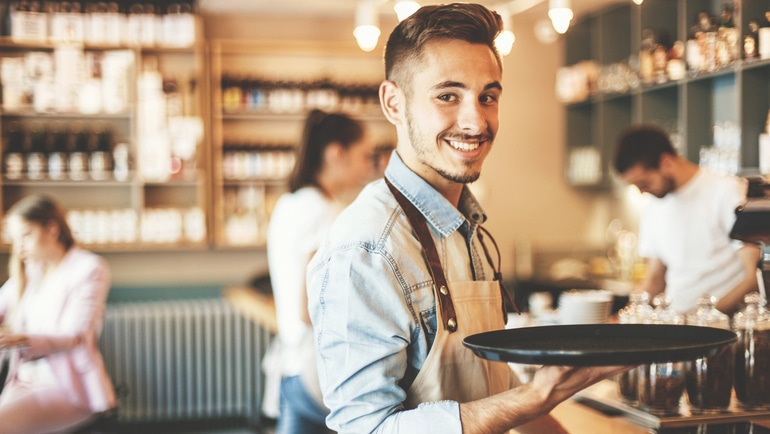 Male server holding a try in a busy restaurant.