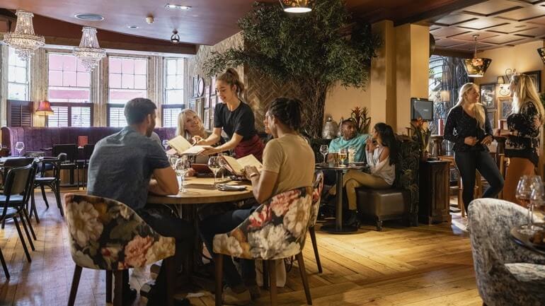 Waitress serving a group at a fine dining restaurant.