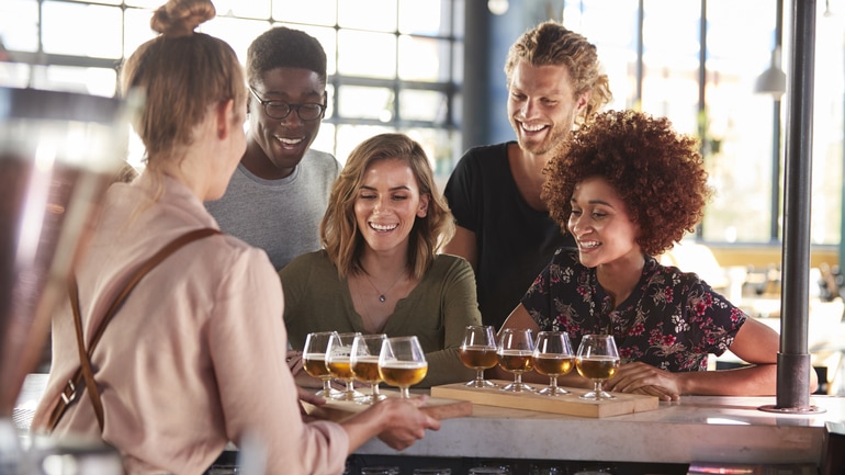 Waitress serving a group Of friends beer at a brewery.
