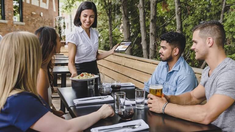 Waitress serving a group while holding a POS.