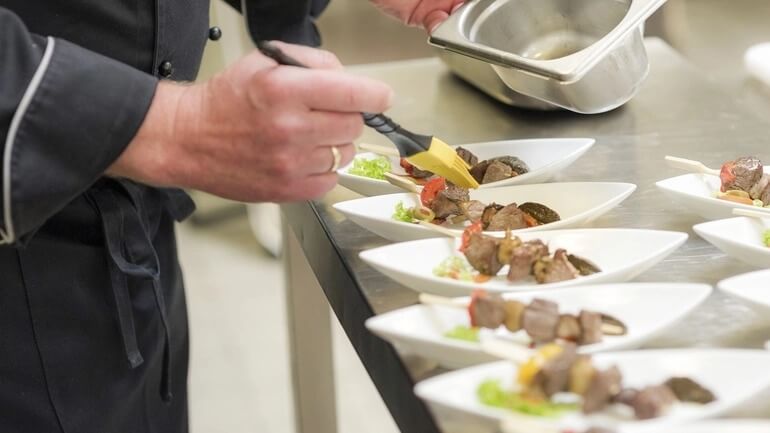 A chef prepares small portion in a restaurant kitchen.