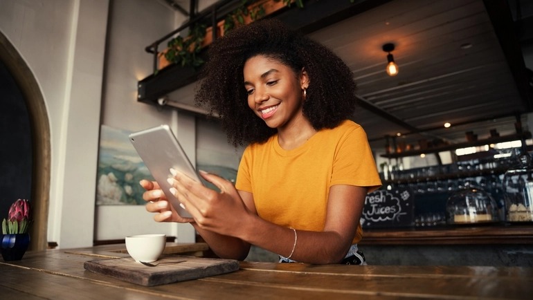 Woman reads a newsletter on her tablet in a restaurant.