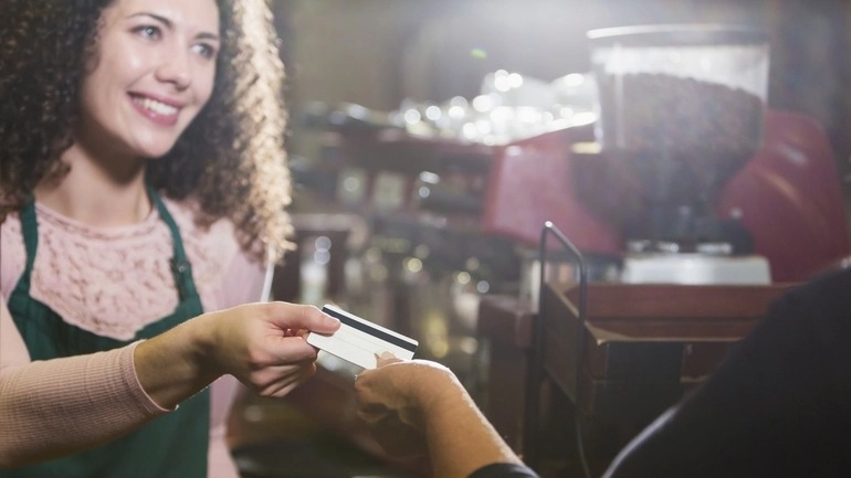 Customer handing a restaurant gift card to a cashier at a coffee shop.