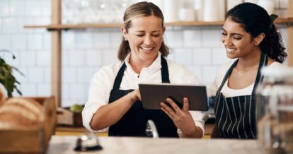 A female restaurant manager trains a new female hire in a restaurant.
