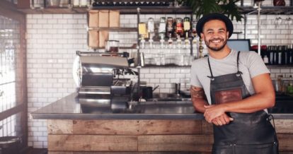 Smiling barista standing in front of a modern coffee bar.