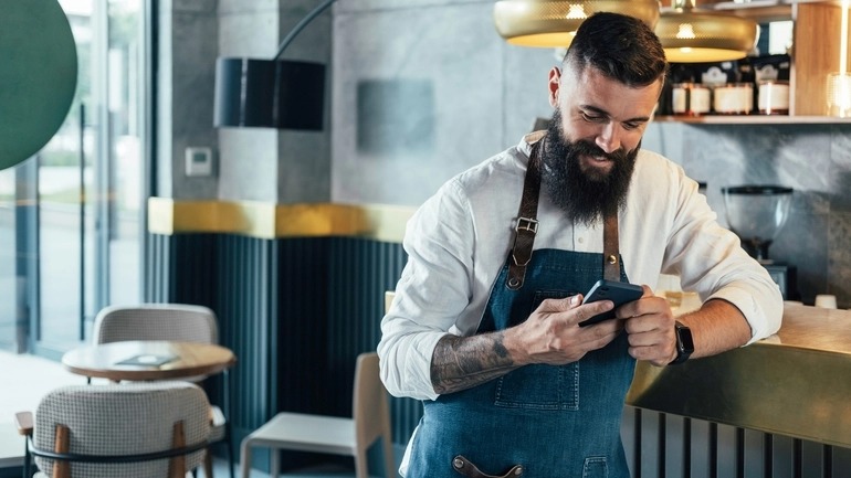 Man Server looks at phone in a restaurant.