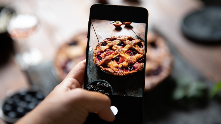 A person photographs a german lattice fruit pie.