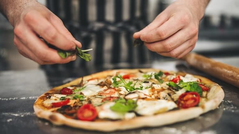 Chef prepares pizza in a restaurant.