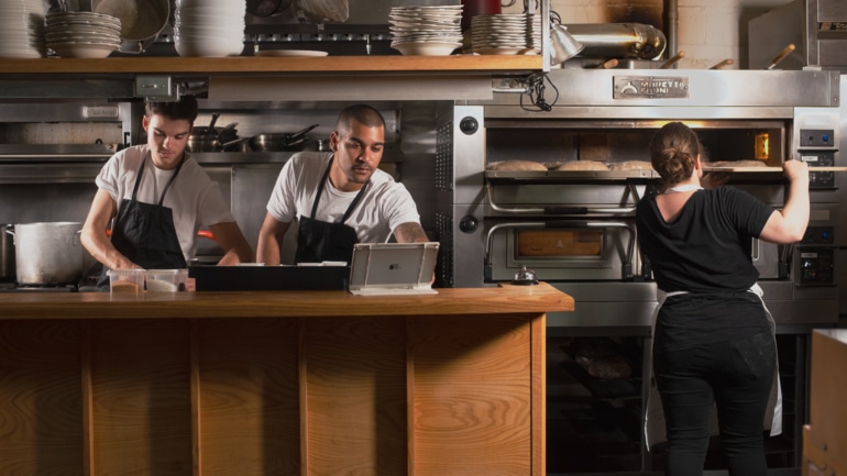 Two cooks using a restaurant POS in the kitchen.