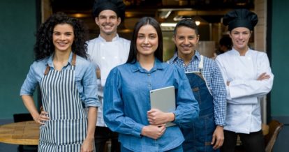 restaurant team portrait smiling and woman holding tablet.