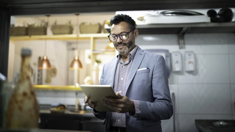 Business owner in restaurant counting inventory on a tablet.