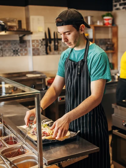 A restaurant employee preparing a burrito