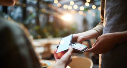 Person dining on a restaurant patio and using their phone to pay for their meal.