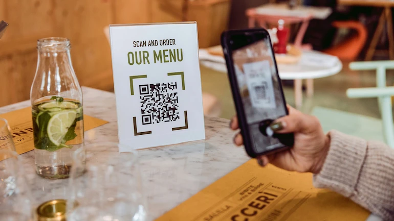 Person scans a QR code on their mobile phone to order from a menu.