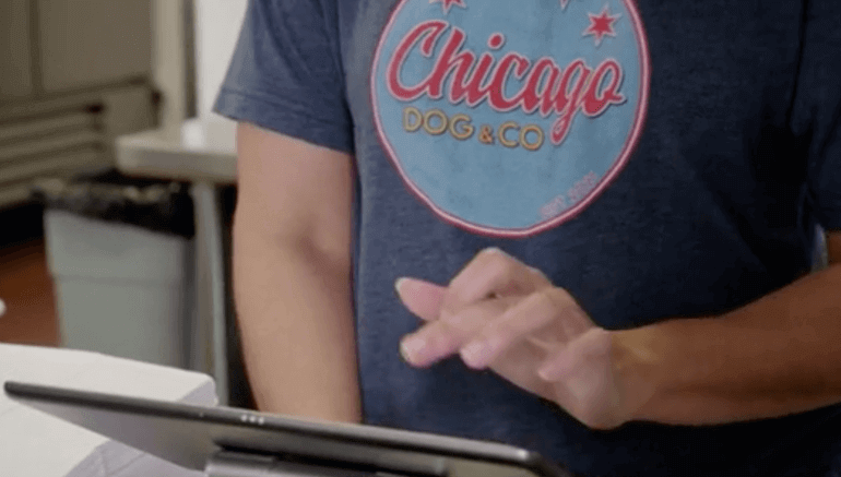 An employee at the Chicago Dog & Co restaurant using an iPad tablet.