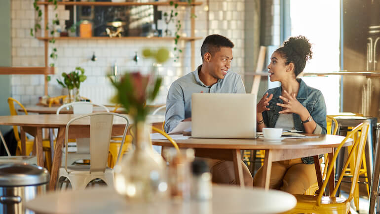 Two young adult business professionals working in a cafe.