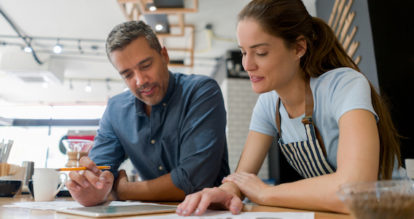 Two restaurant owners working on paper and a tablet.