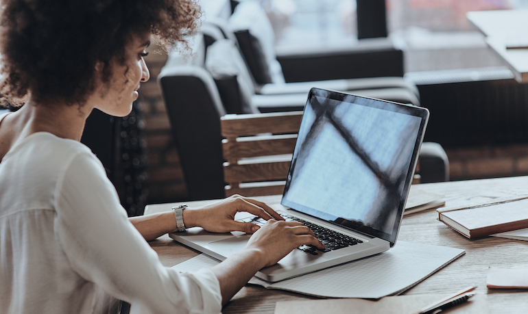 Achieving best results. Rear view of woman using computer while sitting in cafe