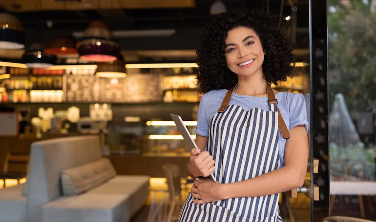 Portrait of a happy waitress working at a restaurant and looking at the camera smiling - food service concepts
