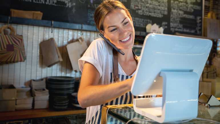 Waitress talking on the phone at a restaurant taking a delivery order and looking happy - food service concepts