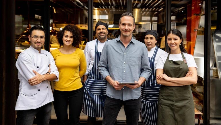 Portrait of a friendly staff working at a restaurant and looking at the camera smiling - food service concepts