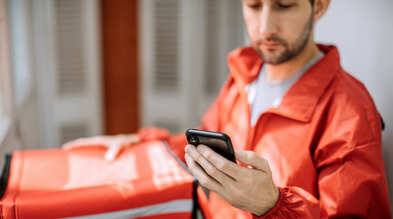 DoorDash delivery driver checking the status of an order on his phone.