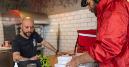 Male delivery person, picking up the food ata restaurant for delivery.