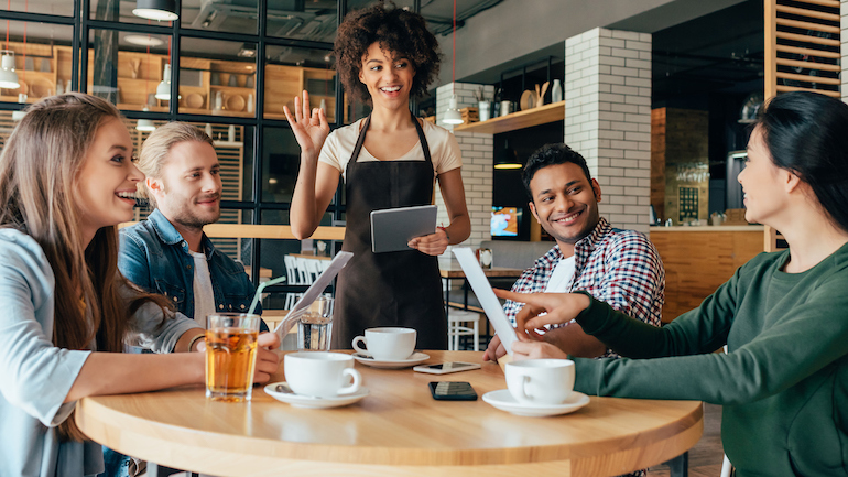 Young african american woman waitress taking orders from clients in cafe