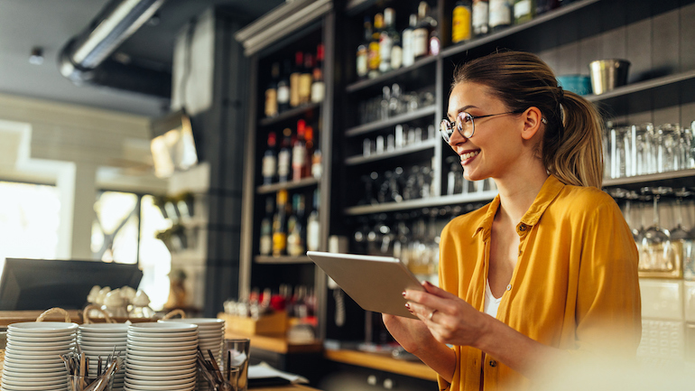 Young woman using a digital tablet while working in a coffee shop