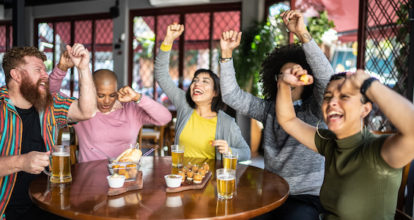 Sports fan friends watching a match and celebrating in a bar