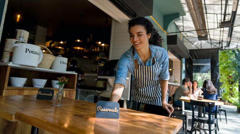 Waitress putting a reserved sign on a table at a restaurant.