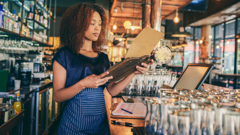 Cropped shot of a waitress looking at paperwork on a clipboard