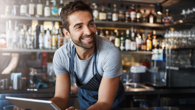 Shot of a young man using a digital tablet while working behind a bar counter