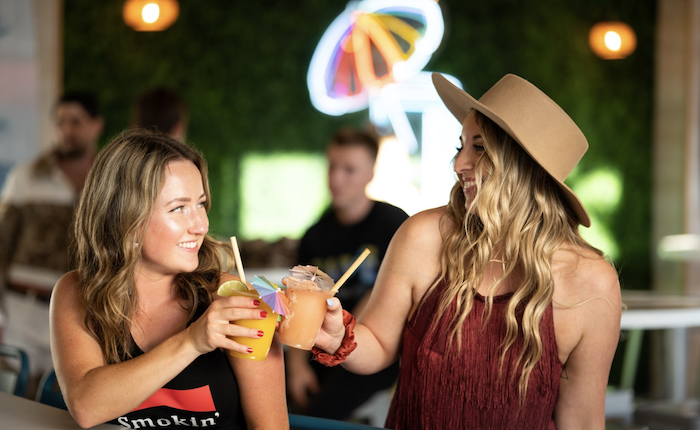 Two smiling women cheersing with cocktails at Zunzi's restaurant.