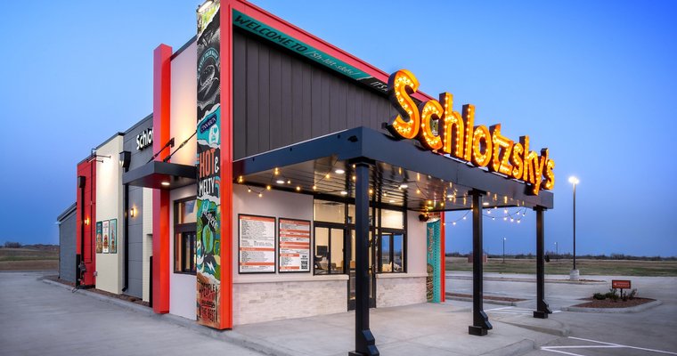 Schlotzsky’s fast food drive-thru with lanes on either side of the building.