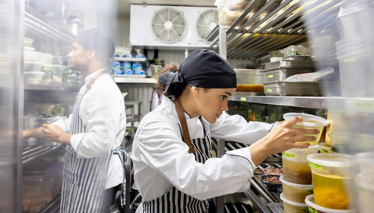 Cooks working at a restaurant and looking for ingredients in the pantry.