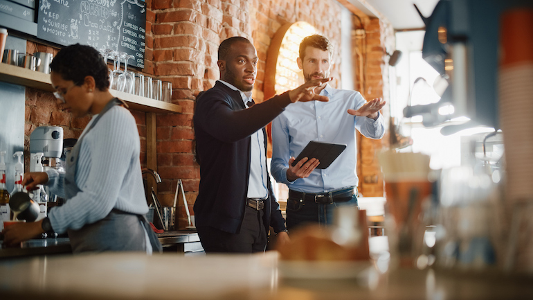 Restaurant managers and barista surveying operations in a cafe.