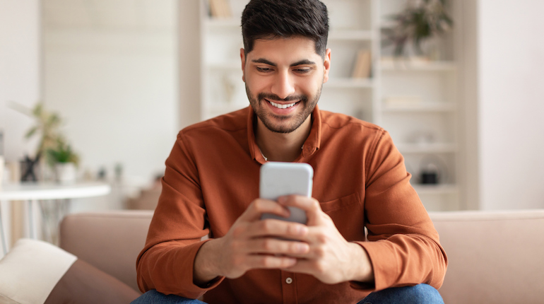 Smiling man using a phone at home.