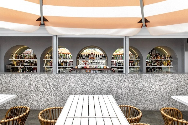 An Italian-inspired bar in Australia with an orange and white striped umbrella overtop.