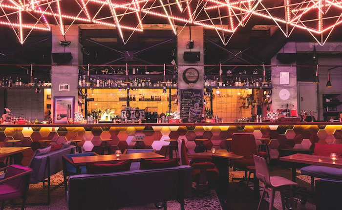 A retro-inspired bar in Sofia, Bulgaria with a geometric design on the bar and intricate lighting overhead.