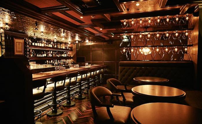 A very dark bar in Shanghai, China that's covered in dark wood paneling and low lights.