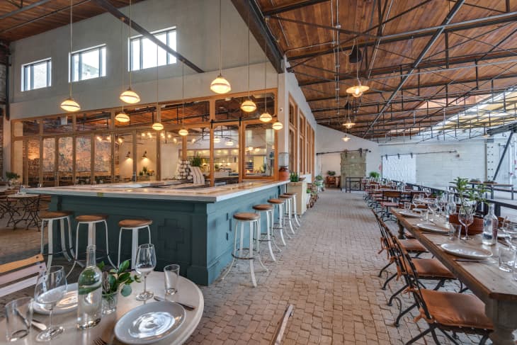 Bright interior of Los Angeles, California’s Manuela restaurant, which features an open bar and wood beams on the ceiling.