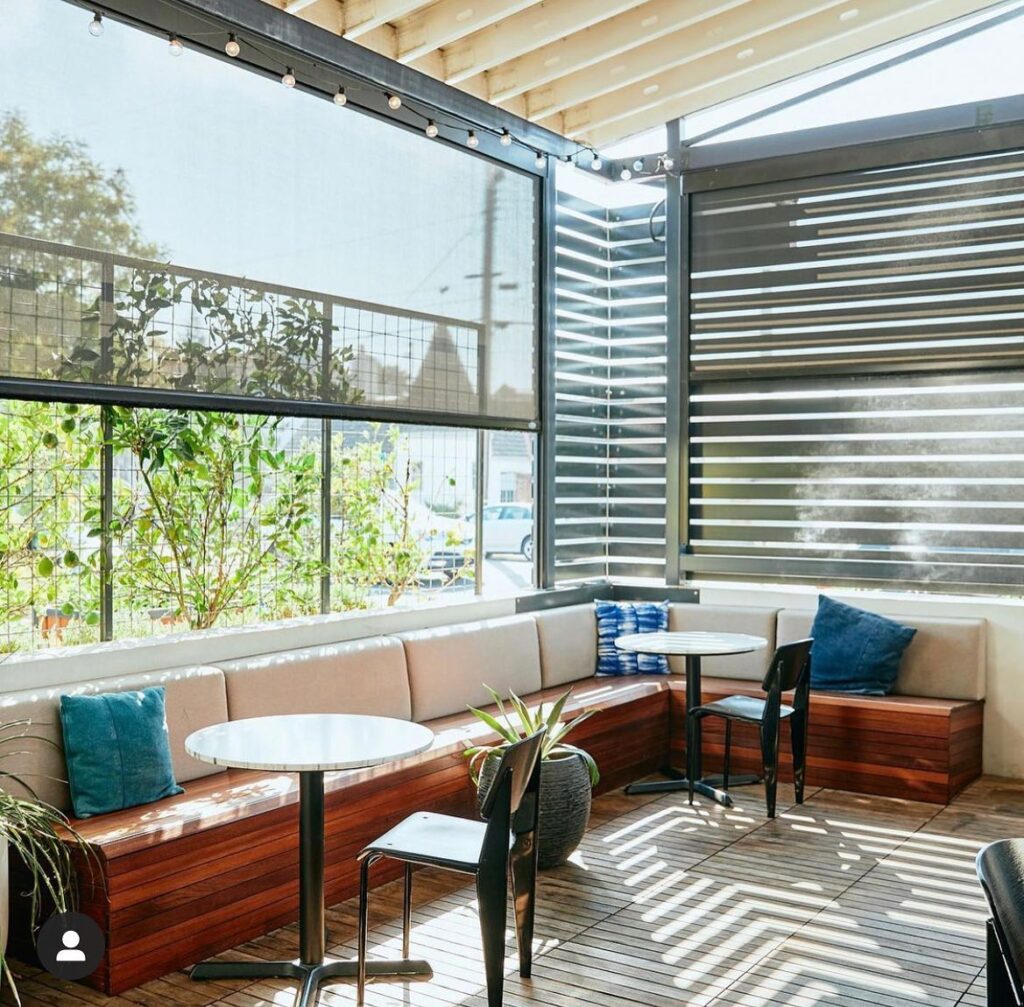 The sun streaming in through wooden slats on the patio of the Canon East Sacramento restaurant.