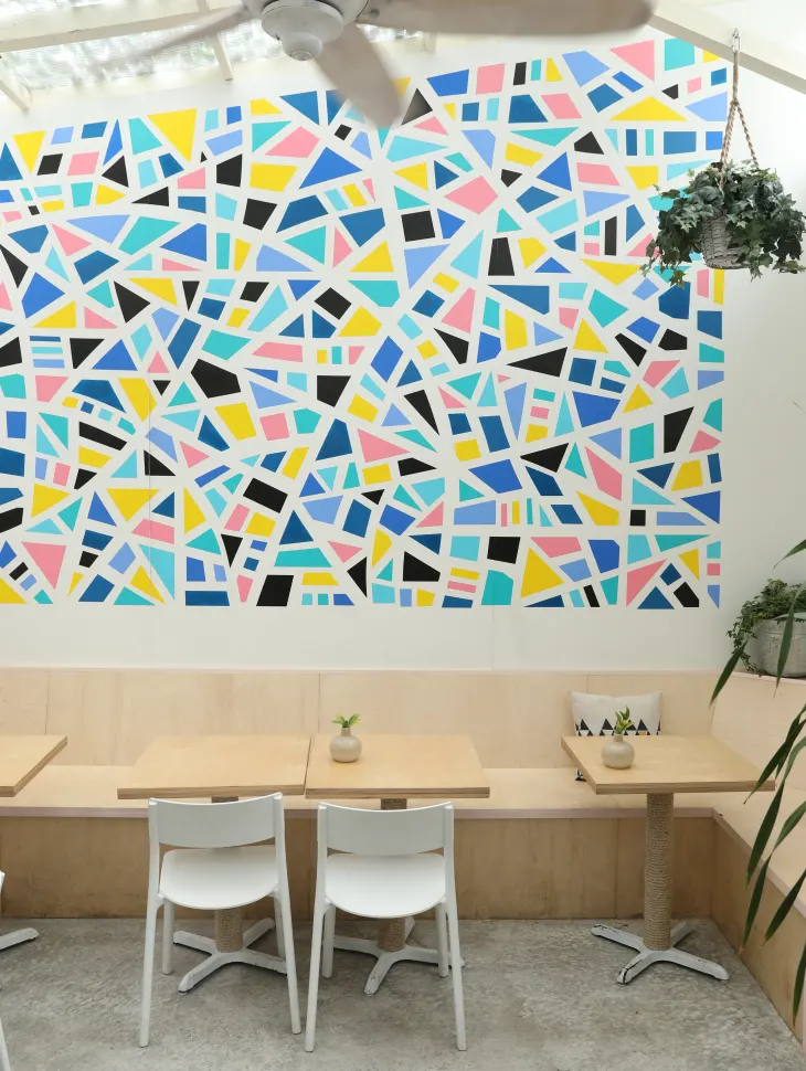 A bright, geometric accent wall above a table at the restaurant Looosie's Kitchen.