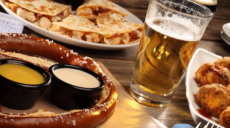 An appetizer trio consisting of a soft pretzel, a quesedilla, and a beer.