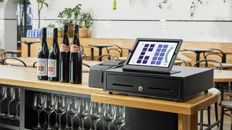 TouchBistro POS open to the floorplan screen sitting on a counter in an empty restaurant.