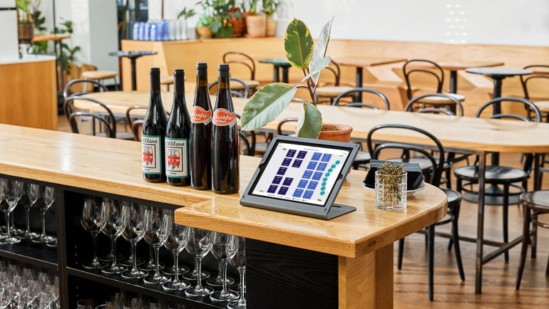 An empty restaurant with an iPad tablet sitting on the bar open to TouchBistro's floorplan screen.