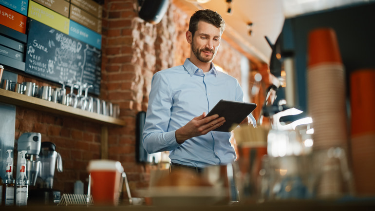 Man wearing a blue colored dress shirt using a tablet at a restaurant.